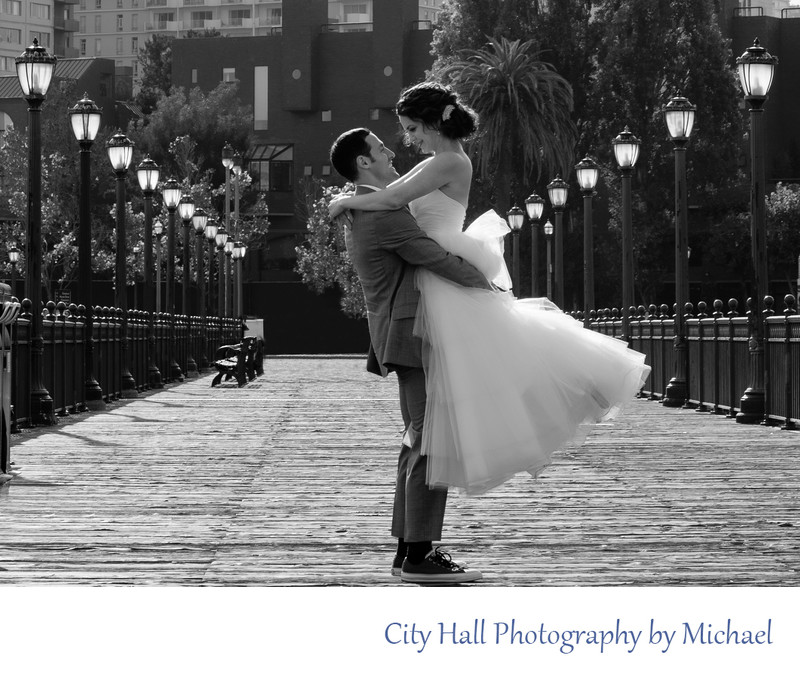 Groom lifting bride on Pier 7 in San Francisco after wedding