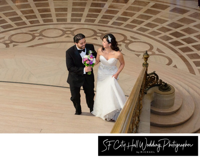 Happy newlyweds walking up the Grand Staircase at SF City Hall