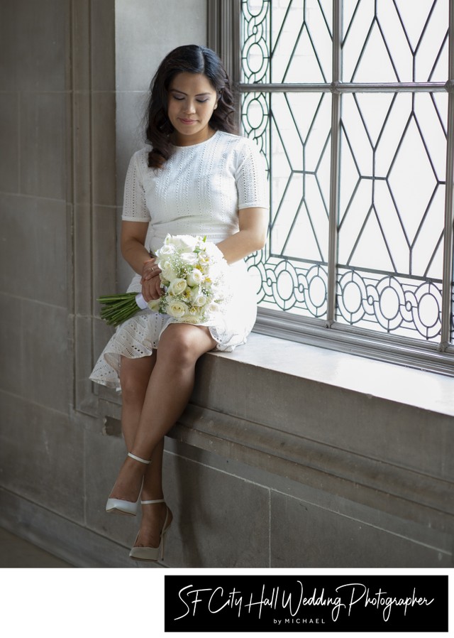 Beautiful Sf City Hall Bride sits in window looking at her flowers