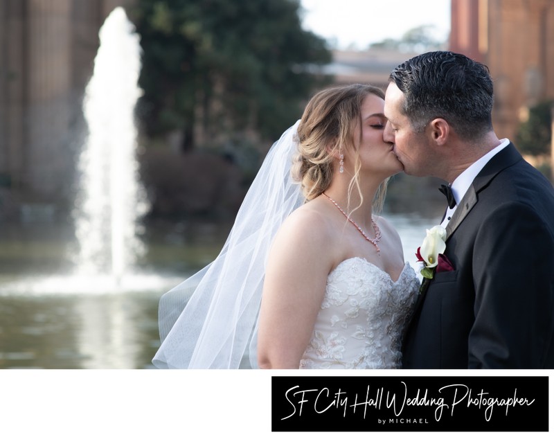Bride and groom kissing by the fountain at the Palace of Fine Arts