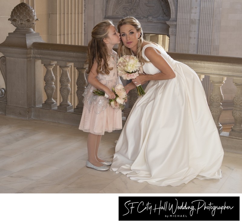 Flower girl kissing bride at SF City Hall
