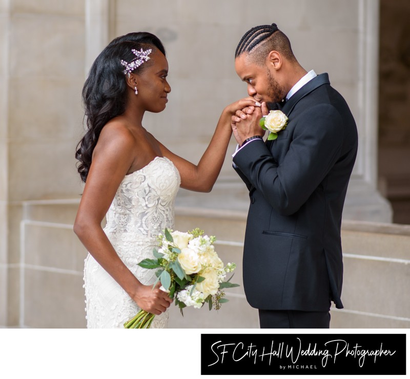 Groom kissing bride's hand after the wedding