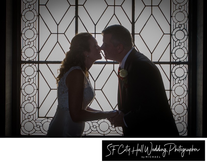 Couple kissing in the window at a San Francisco city hall wedding