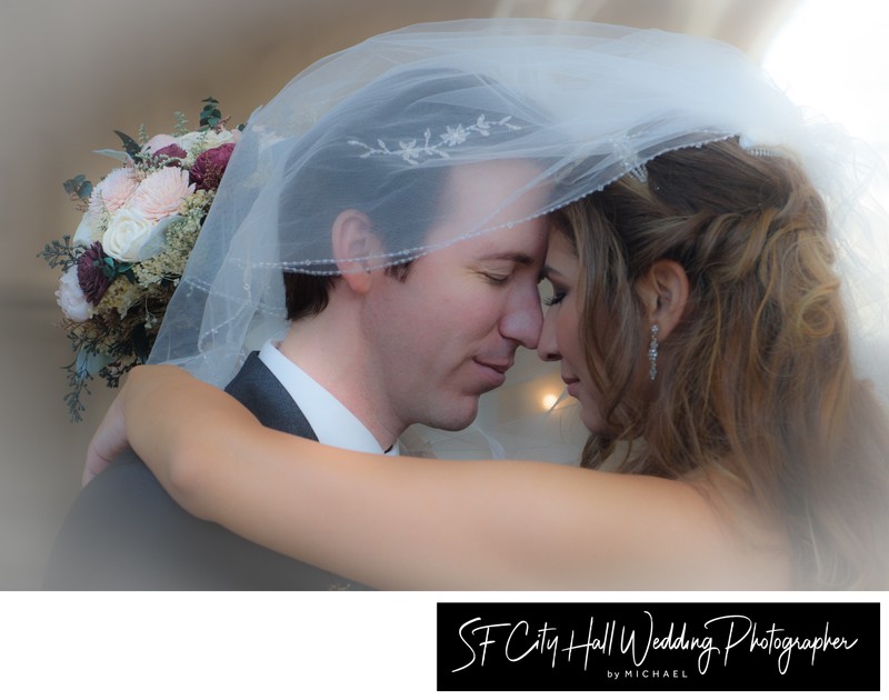 bride and groom sharing  the veil at San Francisco city hall