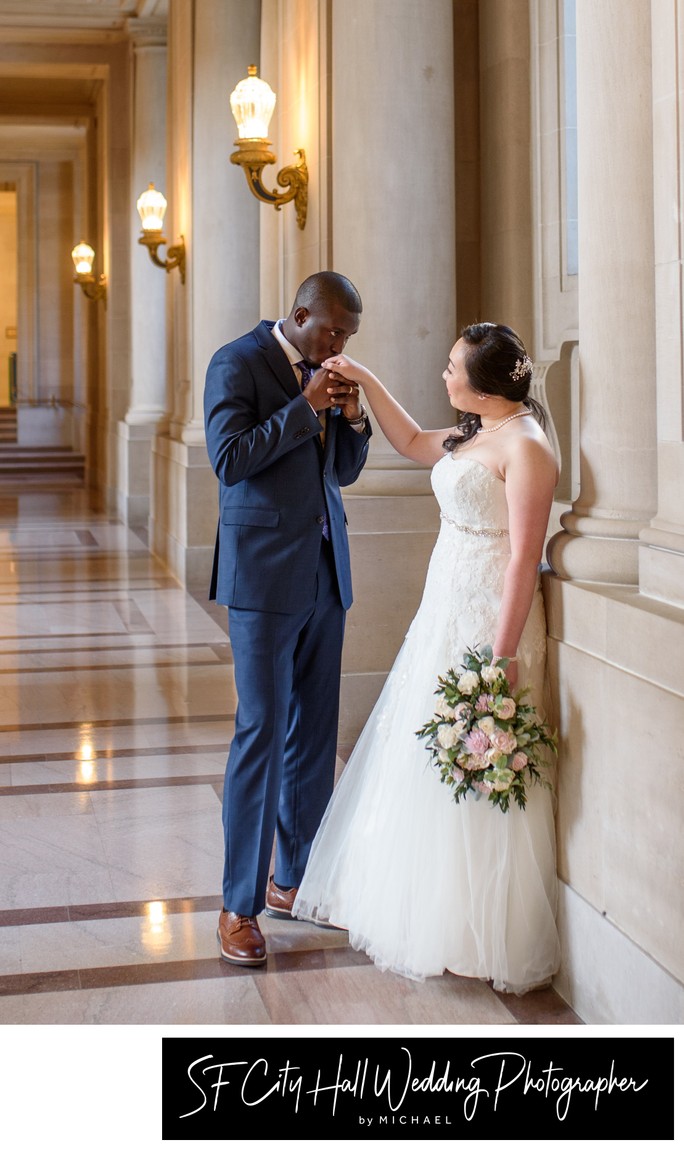 Groom kissing bride on her hand at San Francisco city hall