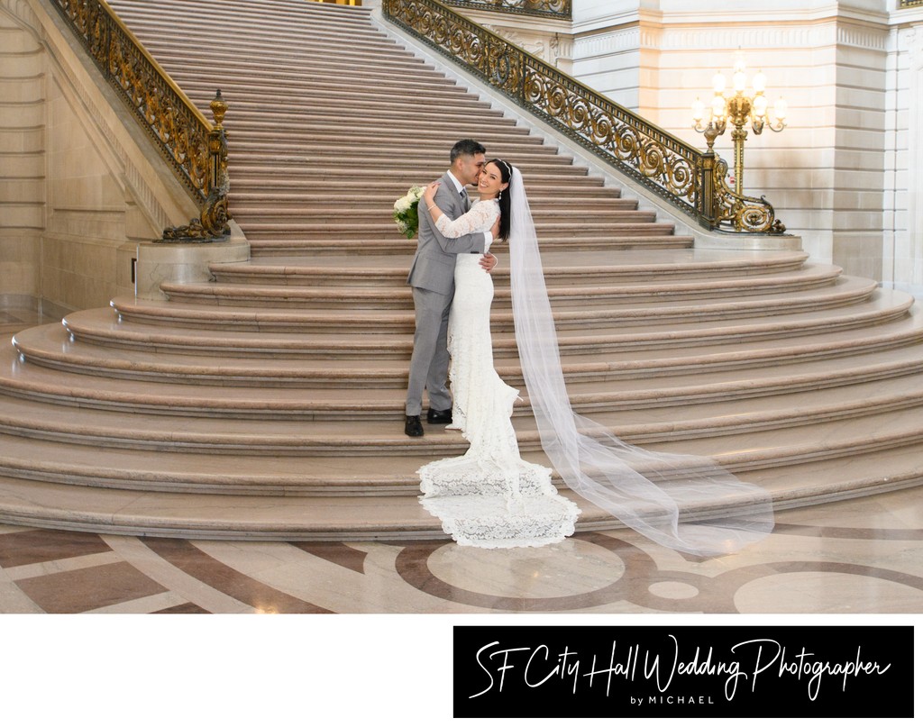 Groom kisses bride on the Grand Staircase at San Francisco city hall