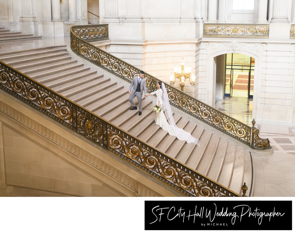 SF City Hall groom assists his bride at the Grand Staircase