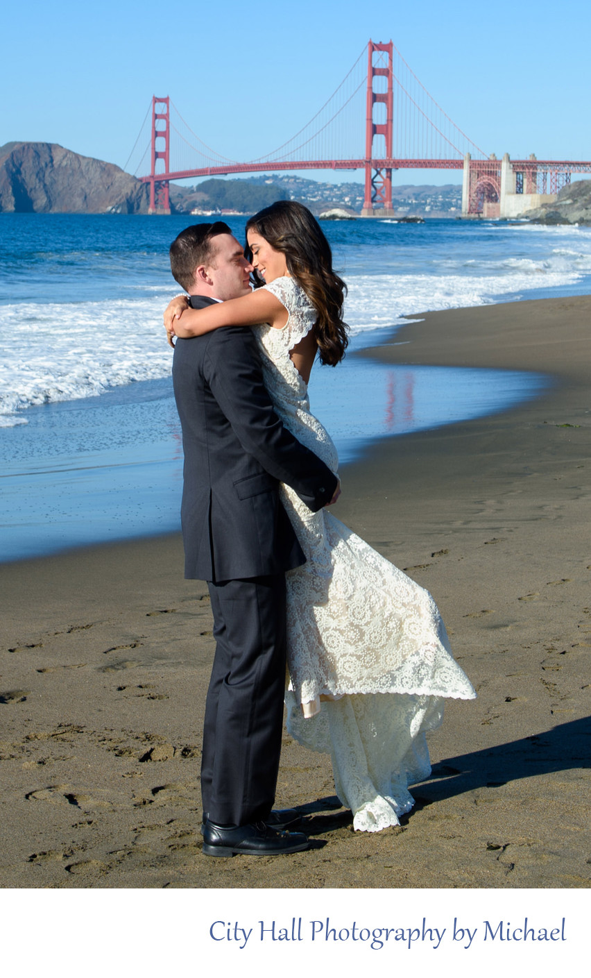 Groom Lifting Bride on Baker Beach with Golden Gate Bridge in San Francisco