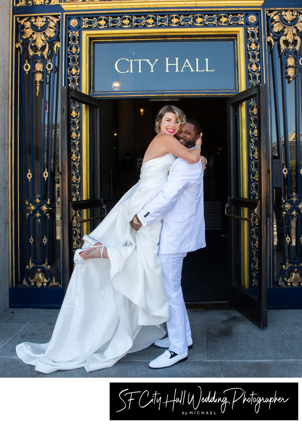 Groom lifting bride at San Francisco city hall sign