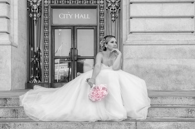 Bride sitting on the steps of San Francisco City Hall
