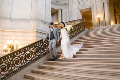 San Francisco city hall newlyweds happily walking down the Grand Staircase