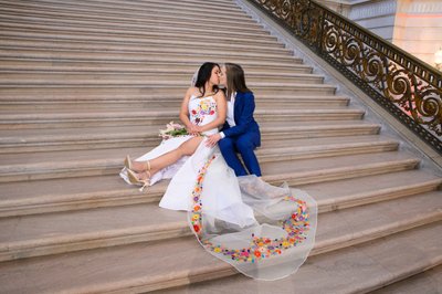 LGBTQ+ brides kissing on the Grand Staircase at San Francisco city hall