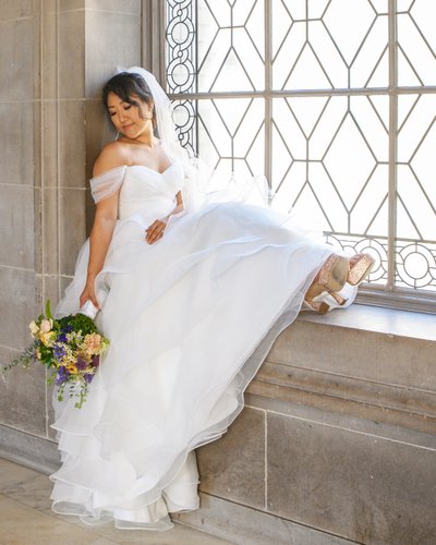 Beautiful Asian bride resting on the window sill at SF City Hall