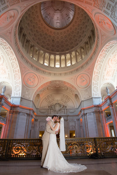 Beautiful colors on the Mayor's Balcony San Francisco City Hall with a bride and groom posing for the camera