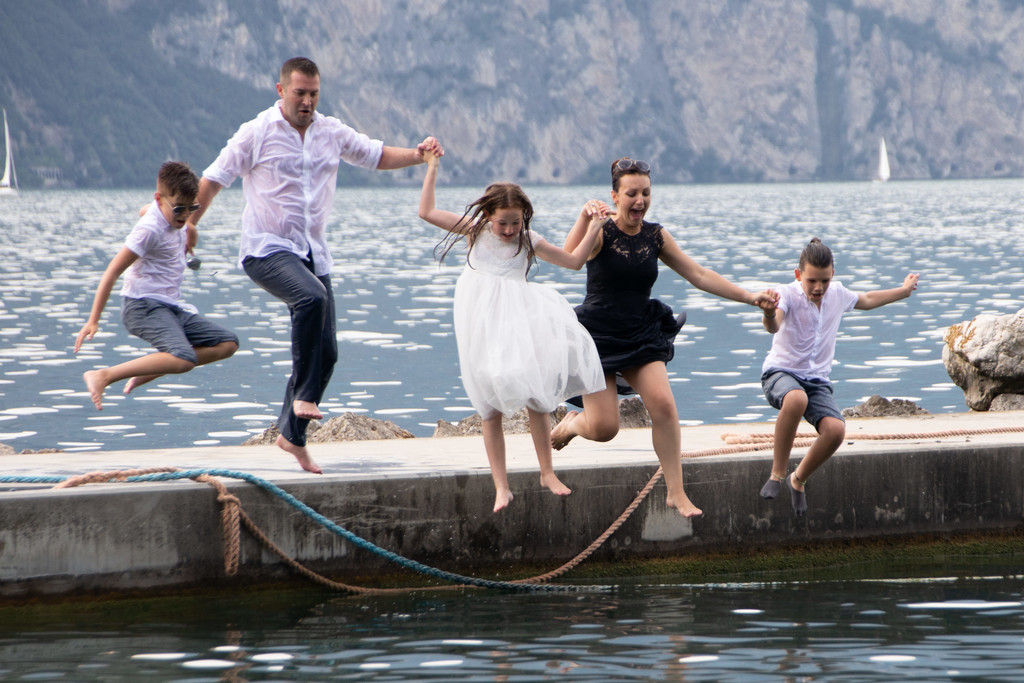 Bride & groom with family jumping in  Lake Garda