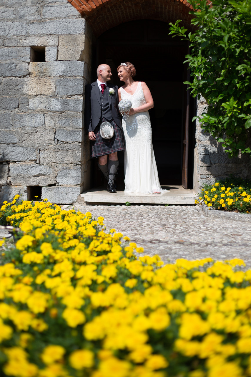 happy bridal couple with flowers in Malcesine castle