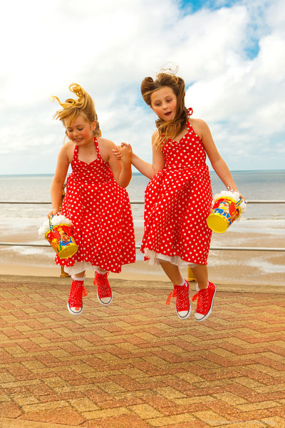 Flower girls jumping in red polka dot dresses