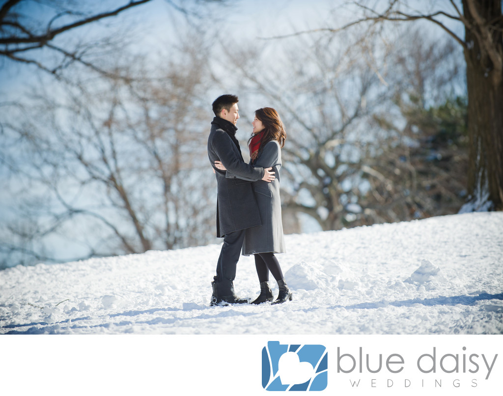 Engaged couple embrace in snowy Central Park NYC