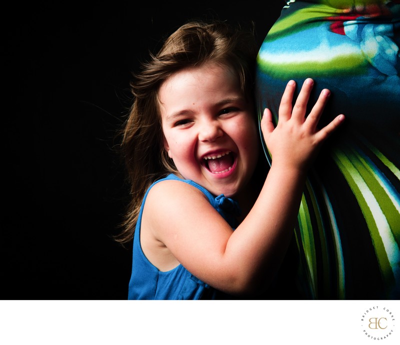 Young Girl Laughing While Hugging Colourful Baby Bump