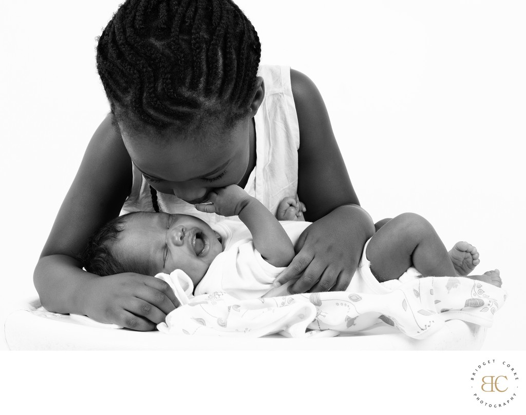 Sister Staring At Newborn Brother