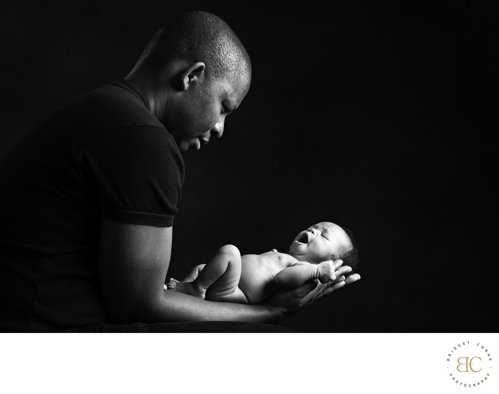 Newborn's First Gaze: Father's Gentle Hold