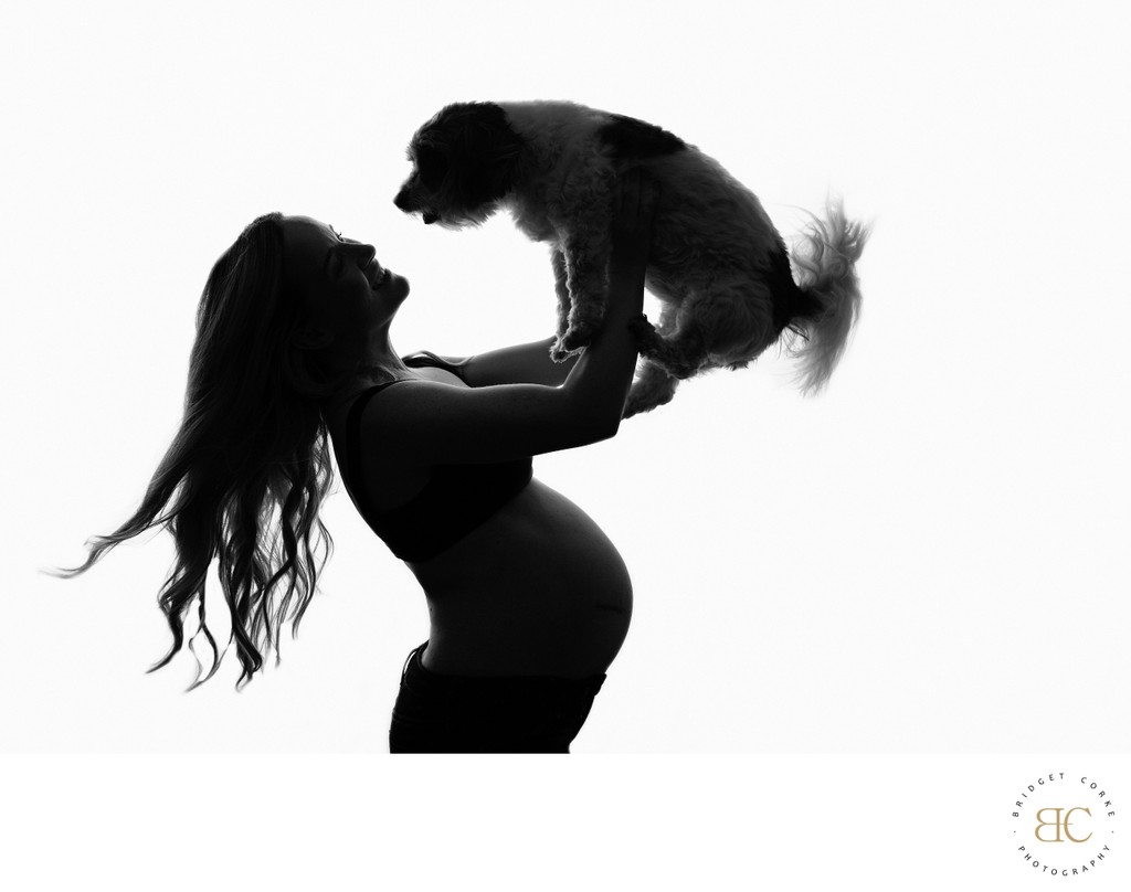 Silhouette of Pregnant Woman Lifting Dog