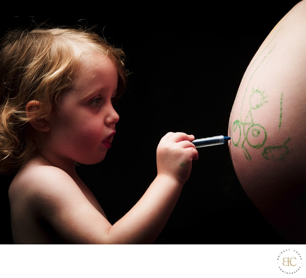 Young Child Creating Art on Mother's Baby Bump