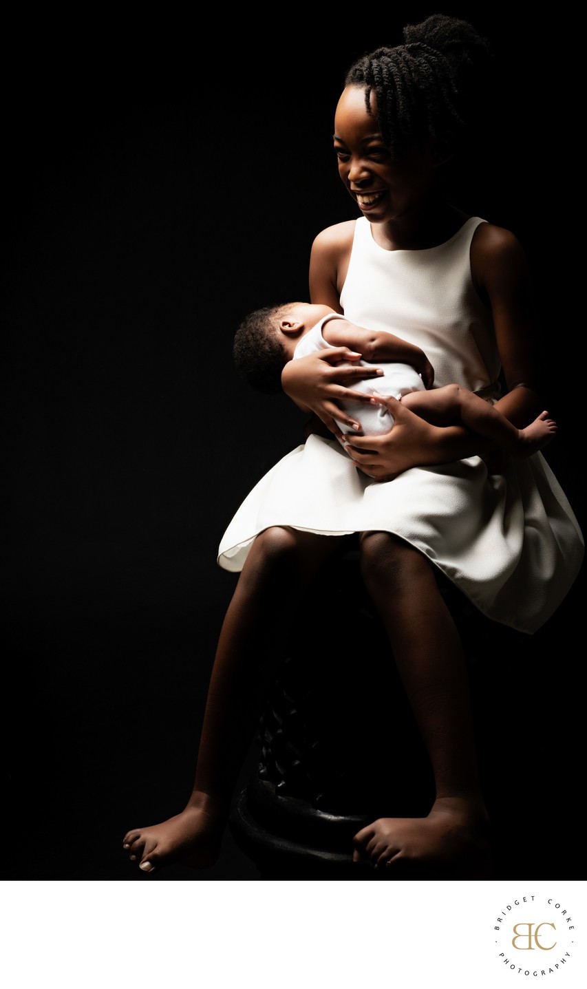 Delighted SIbling Holding Newborn Sister