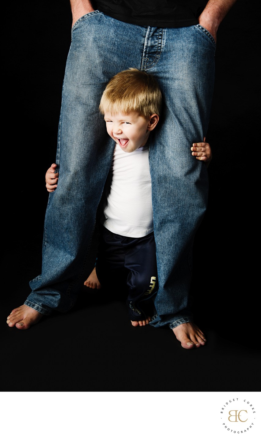 Playful Child Peeking Through Father's Legs