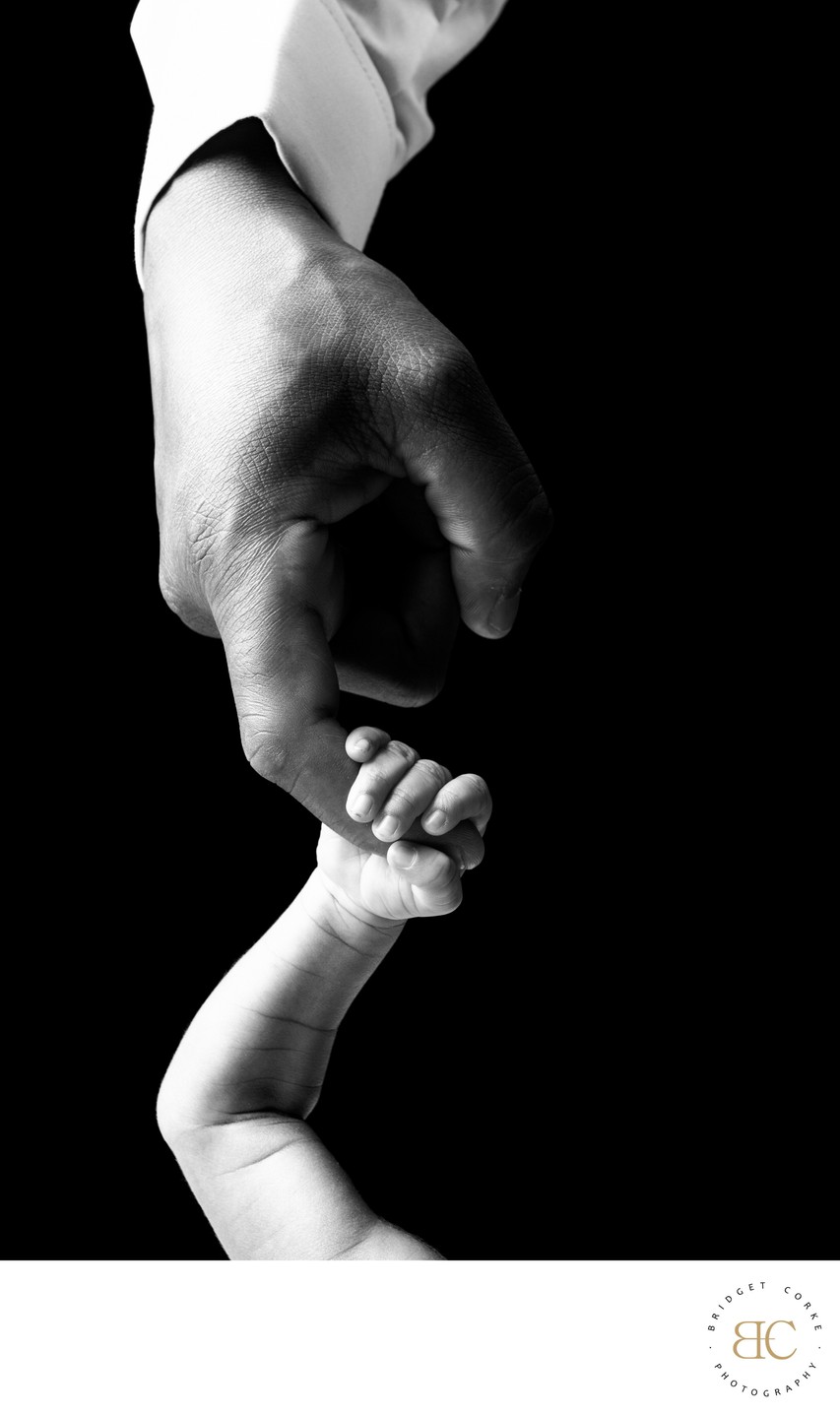 Connection in Contrast: Newborn's Hand in Adult's Grip