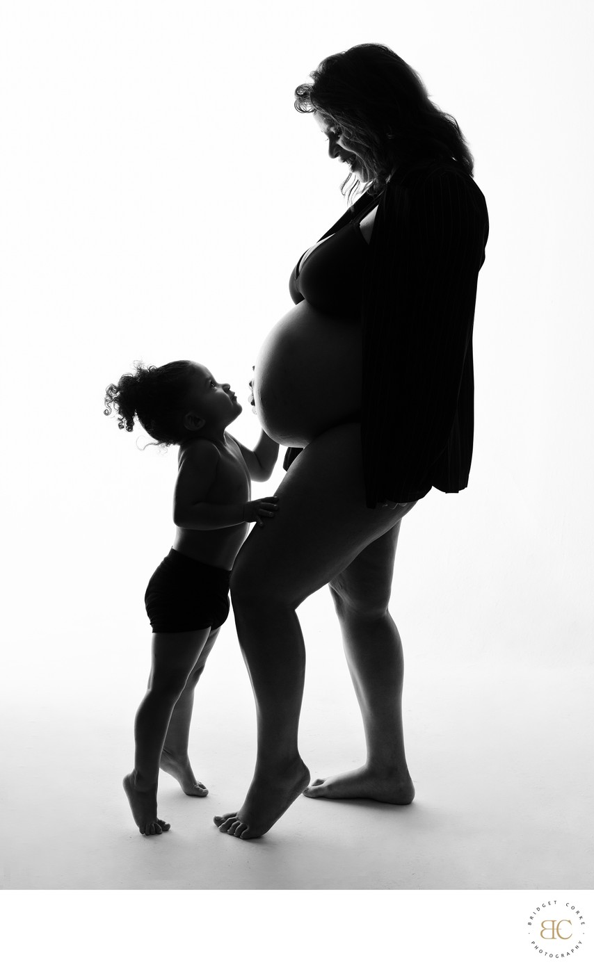 Silhouette of Child Kissing Mother’s Bump