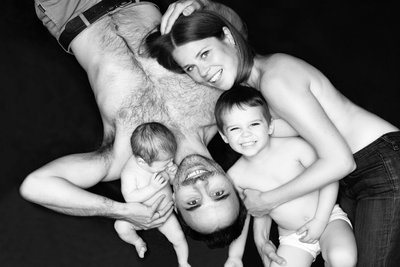 Shirtless Family Lying Holding Newborn