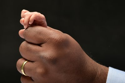 Newborn Fingers Popping Out of Dad's Hand