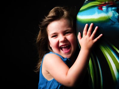 Young Girl Laughing While Hugging Colourful Baby Bump