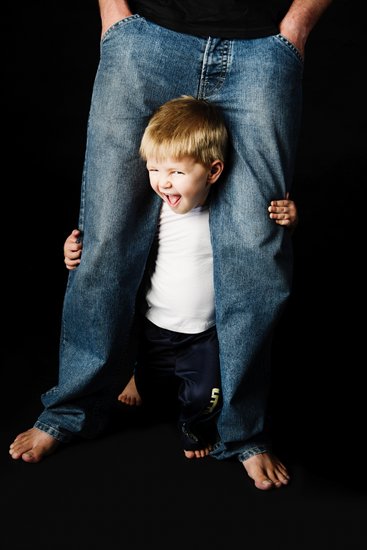 Playful Child Peeking Through Father's Legs