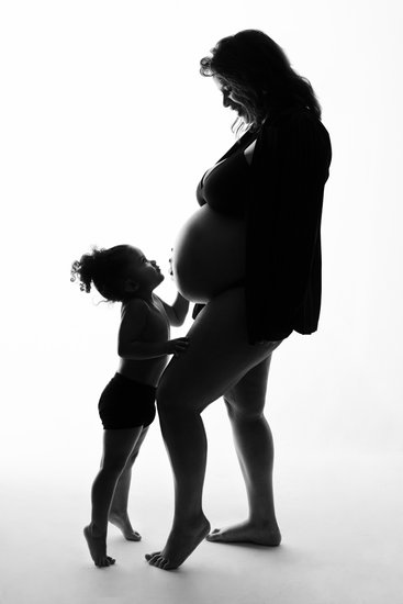 Silhouette of Child Kissing Mother’s Bump