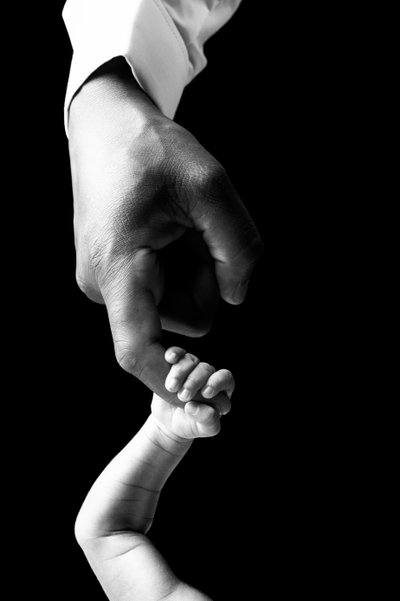 Connection in Contrast: Newborn's Hand in Adult's Grip