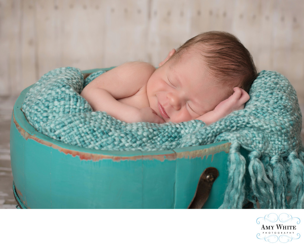 Smiling Baby in bucket Cedar Rapids newborn photoshoot 