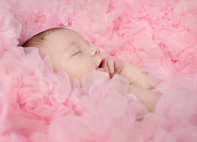 Happy newborn surrounded by pink ruffles 