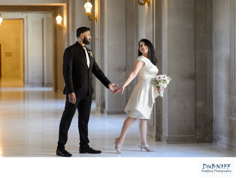 San Francisco city hall bride looking amazing  as she looks back at her groom