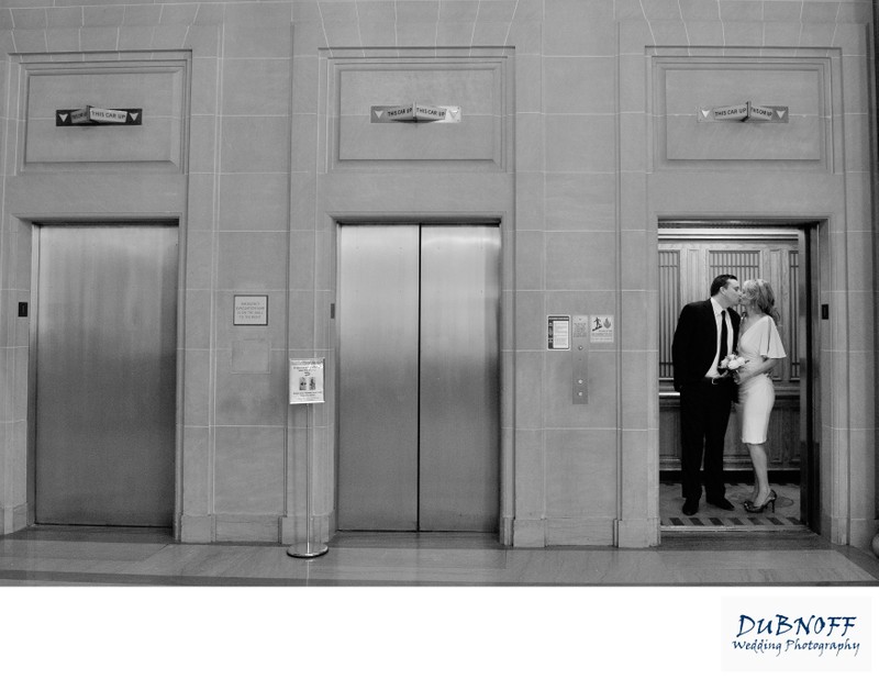 Elevator wedding photo at San Francisco city hall with bride and groom kissing