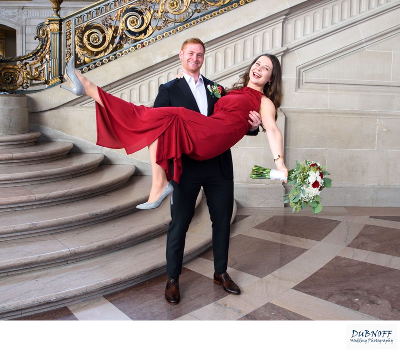 Groom lifting bride in red dress by the Grand Staircase - Wedding Photography