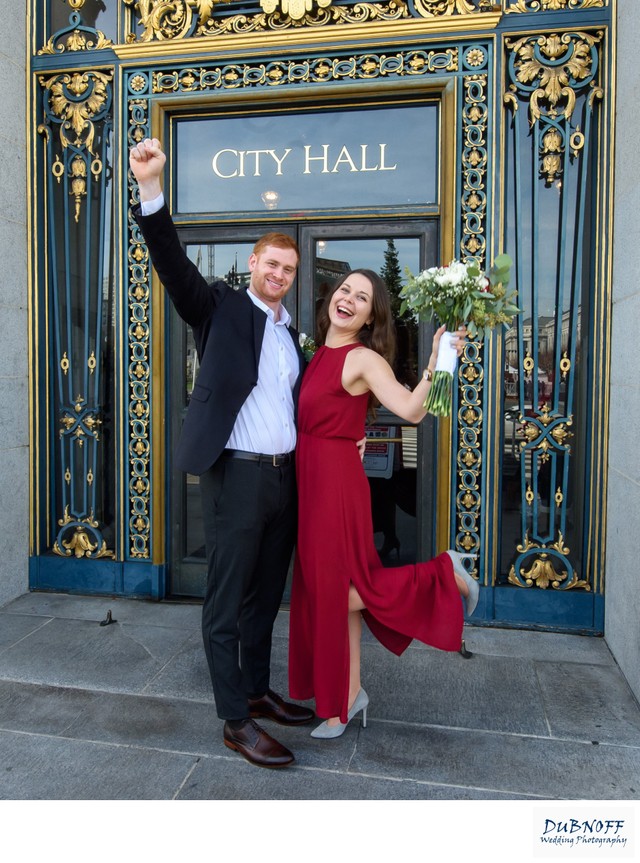 Bride in red wedding dress celebrates for the camera in San Francisco