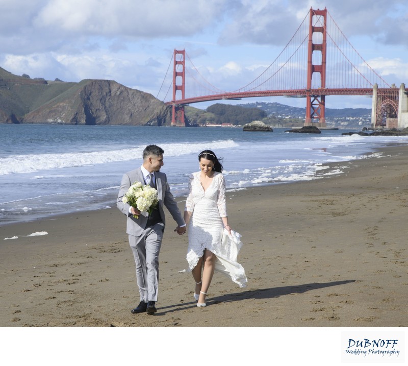 City Hall wedding couple walking at Baker Beach with the Golden Gate Bridge
