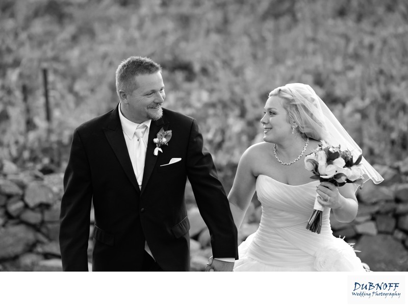 Black and white image of bride and groom walking