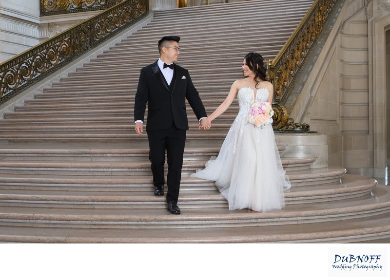 Happy newlyweds walking down the Grand Staircase at SF City Hall