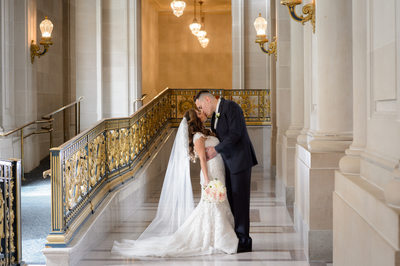 Groom Kissing Bride with glowing veil at San Francisco City Hall