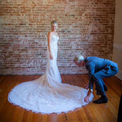 Groom helping his new bride with her dress train