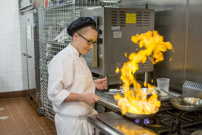 Culinary student flaming meat in college classroom
