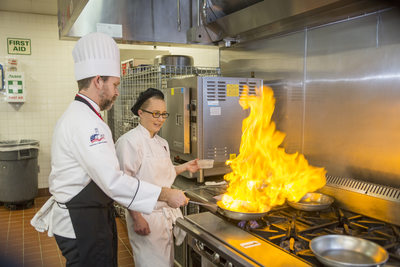 Flaming meat in teaching kitchen at culinary college
